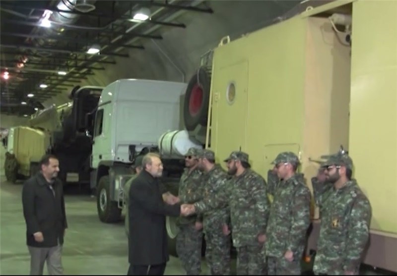 Ali Larijani greets uniformed base personnel beside an Emad missile launcher in an underground gallery